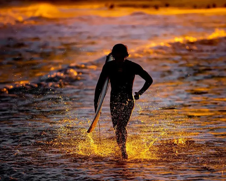 Surfer through backlit splash